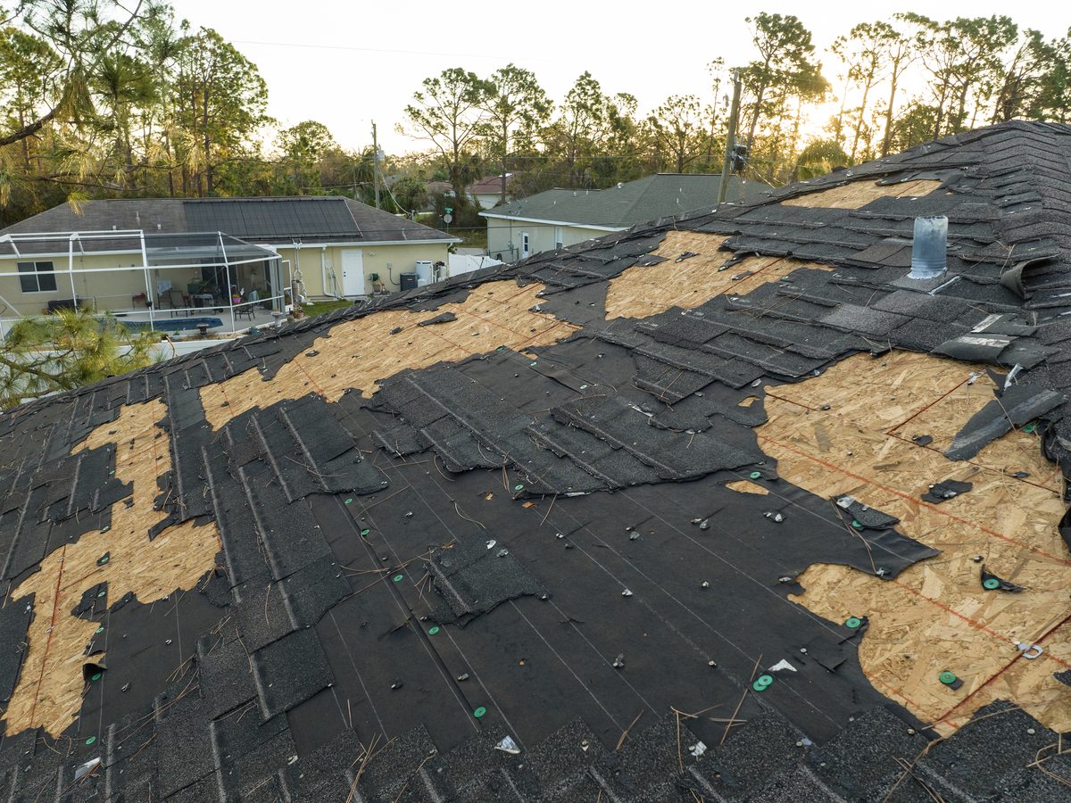 Wind-damaged roof with missing asphalt shingles awaiting inspection
